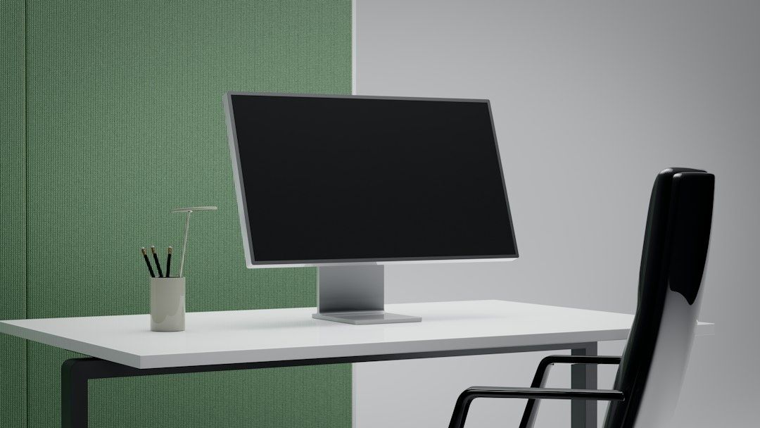 Modern arbetsplats med datorskärm på vitt skrivbord och kontorsstol