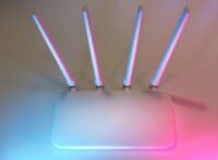 Vit wifi-router med fyra antenner i blått och rosa ljus