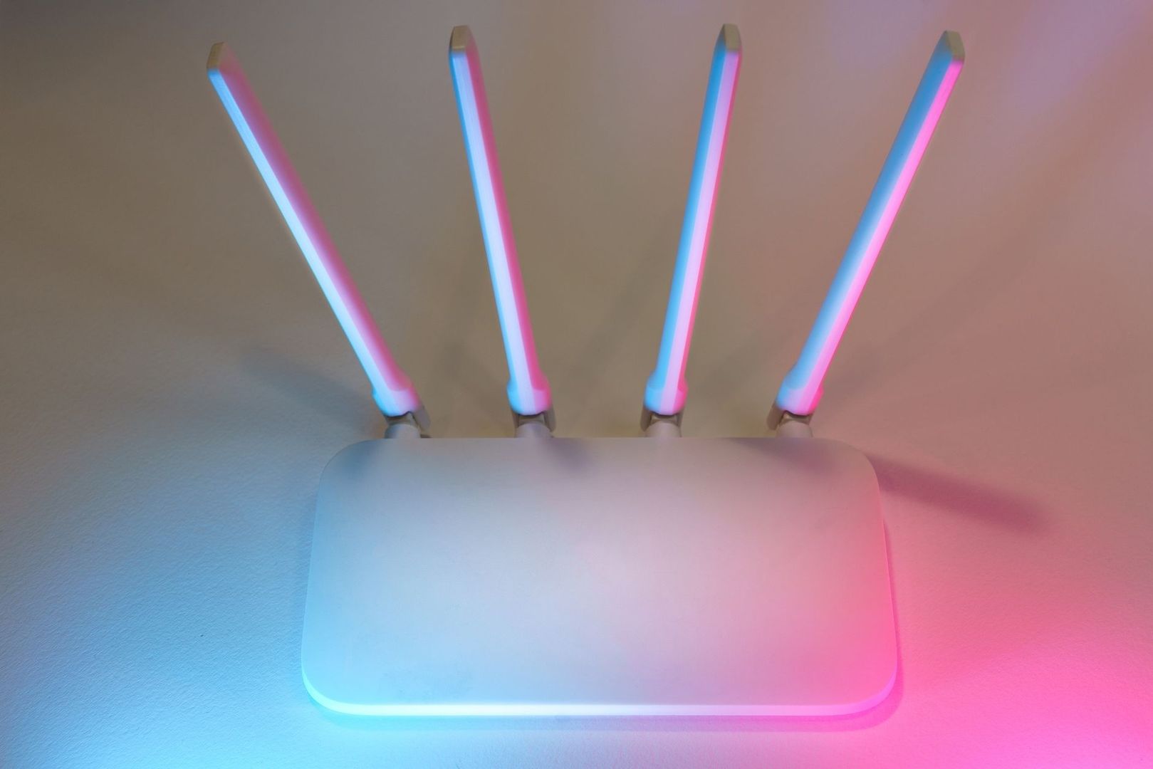 Vit wifi-router med fyra antenner i blått och rosa ljus